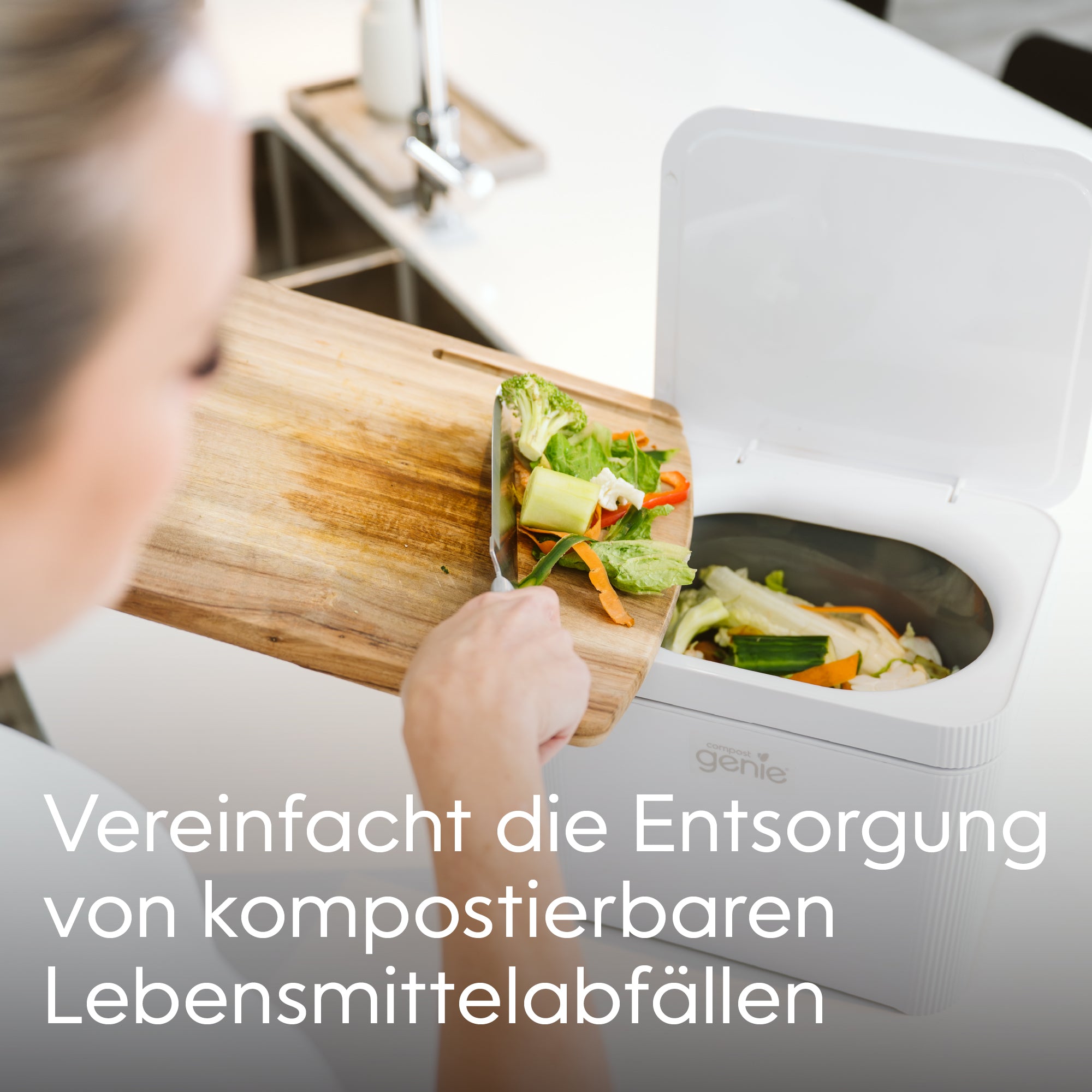 Person disposing of food waste into a compostable bin with text in German_DE-DE