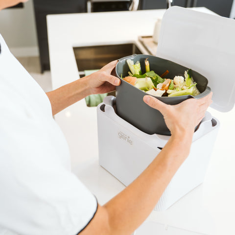 Person using a kitchen compost bin with food waste in a modern kitchen_UK-EN