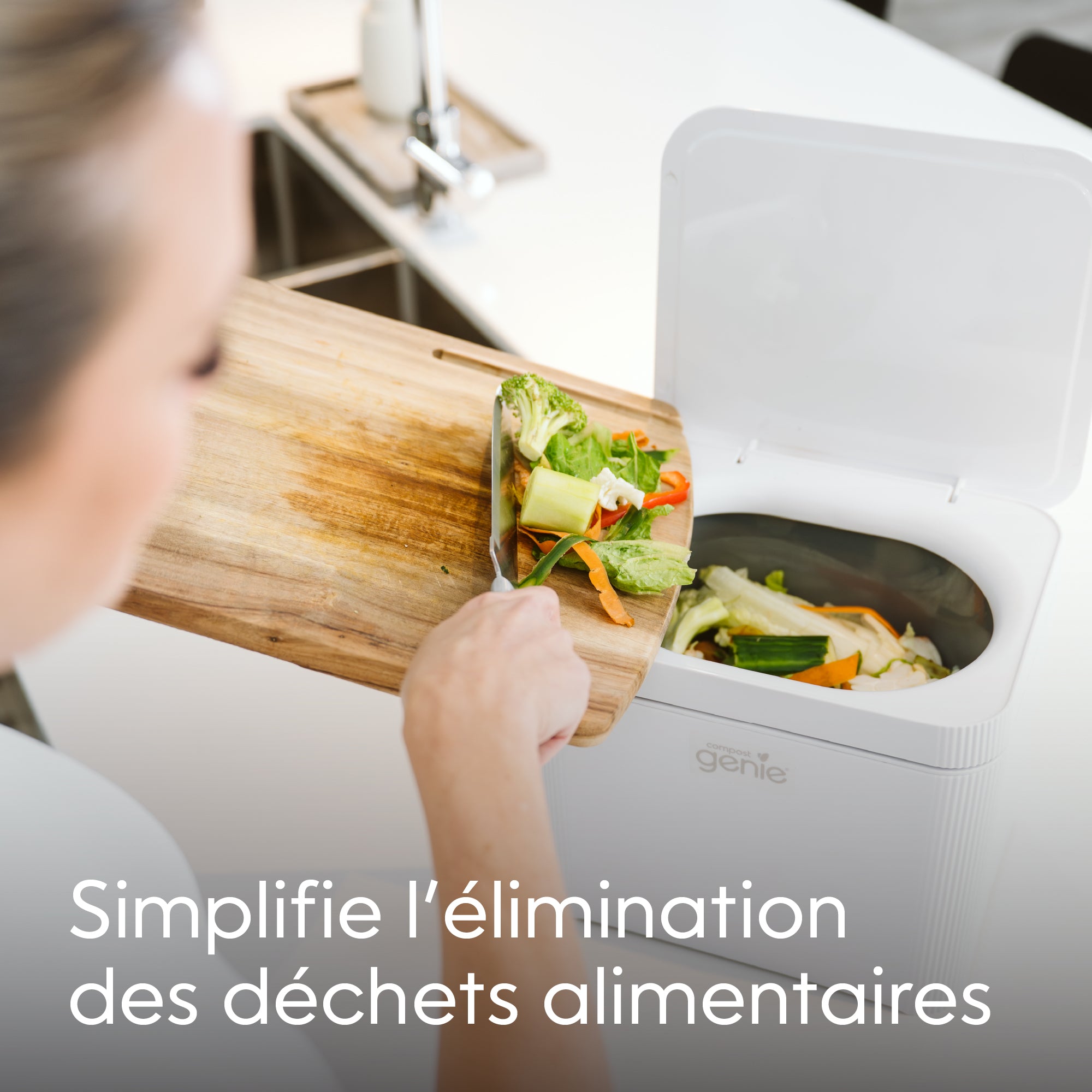 Person disposing food waste into a white compost bin with text 'Simplifie l'elimination des dechets alimentaires'_FR-FR