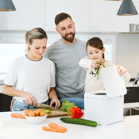 Family of three in a kitchen preparing vegetables_FR-FR